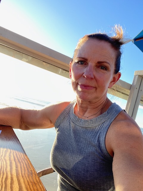 Female seated in the outdoors with a kind smile in the sunshine